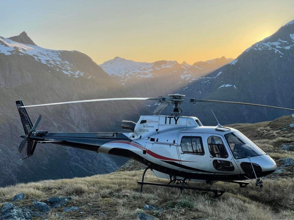 Helicopter landed on hill with mountains in the background